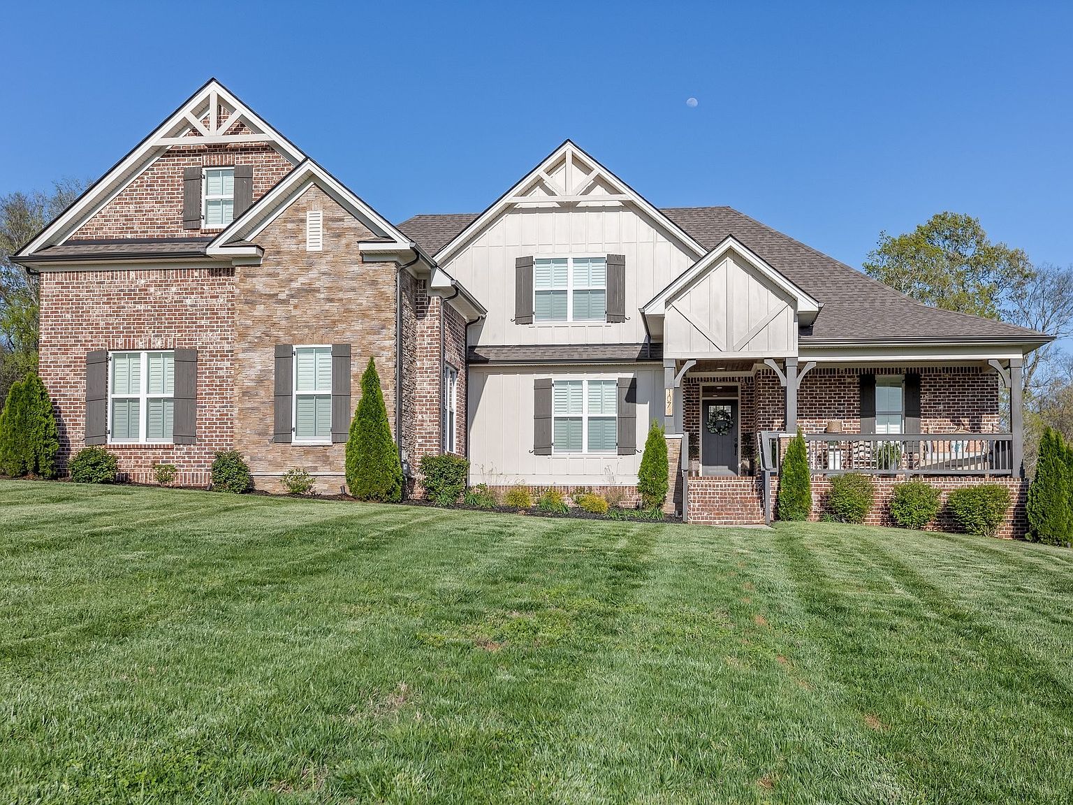 Front elevation of 1070 Hideaway Road, a brick craftsman home with gabled roofline and board-and-batten accents, set behind a manicured lawn in north Columbia, Tennessee